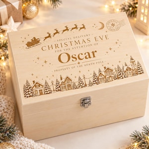 May include: A rectangular light-coloured wooden box with a metal latch. The lid features an engraved design of a sleigh with reindeer, a North Pole postmark, and the text: Special Delivery Christmas Eve for the attention of Oscar.