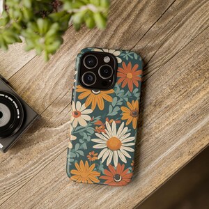 May include: A teal phone case with a floral pattern featuring orange, yellow, and white flowers. The case has a cutout for the phone's camera.