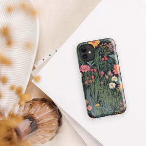 May include: A black phone case with a floral pattern featuring pink, yellow, and red flowers on a dark green background.