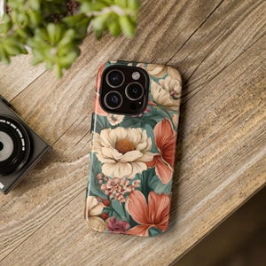 May include: A floral phone case with a teal background and pink, white, and yellow flowers. The case has a camera cutout for a phone with three lenses.