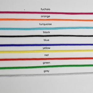 May include: A selection of colorful cords in fuchsia, orange, turquoise, black, blue, yellow, red, green, and grey. Each cord is labeled with its respective color name.