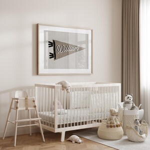May include: A white crib with a white and gray patterned mattress, a white high chair, and a framed print with the text "William" on a brown pennant. There are also several stuffed animals and baskets in the room.