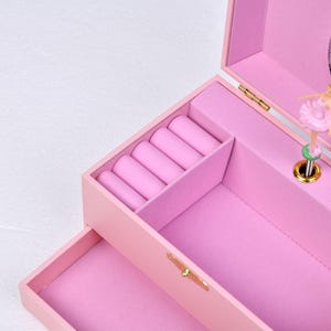 May include: Pink jewelry box with a ballerina music box inside. The box has a mirror and a ring holder.