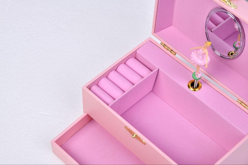 May include: Pink jewelry box with a ballerina music box inside. The box has a mirror and a ring holder.