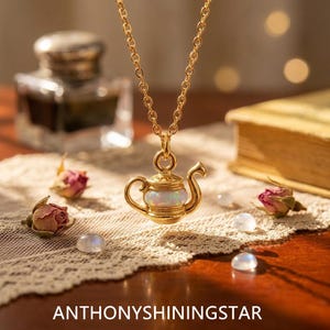 May include: A gold-toned necklace featuring a pendant shaped like a miniature teapot with a central iridescent opal-like stone. The pendant hangs from a delicate gold-toned chain. The text ANTHONYSHININGSTAR is printed at the bottom.