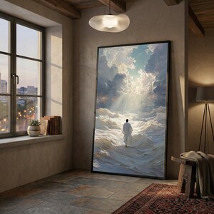 Könnte beinhalten: Großer gerahmter Kunstdruck, der eine Figur in Weiß zeigt, die durch weiße Wellen unter einem bewölkten Himmel auf ein helles Licht zugeht. Das Kunstwerk wird in einem Raum mit Fenster, Büchern und einer dekorativen Lampe ausgestellt.