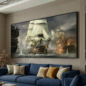 May include: Large framed canvas art depicting a dramatic naval battle scene with tall ships, billowing sails, and cannon fire. The artwork features a dark, stormy sky and a detailed depiction of the ships at sea. The canvas is framed in black and hangs above a blue sofa.