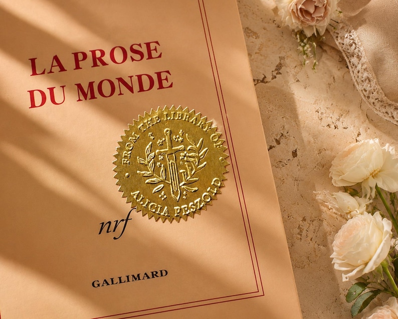 Peut inclure: Un livre intitul&eacute; "LA PROSE DU MONDE" avec du texte rouge sur une couverture beige clair. Un sceau dor&eacute; avec une &eacute;p&eacute;e et une couronne est appos&eacute; sur la couverture. Le livre est de la biblioth&egrave;que d'Alicia Peszold, publi&eacute; par Gallimard.