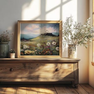 May include: A framed landscape painting depicts a grassy hill with three crosses under a cloudy sky. The foreground features a field of wildflowers in various colors. The painting is displayed on a wooden dresser, with vases of flowers and plants.