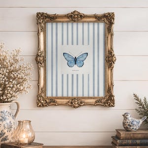 May include: A rectangular wall art print featuring a centered blue butterfly illustration on a white background with vertical light blue stripes, enclosed in an ornate, antique-style gold frame with intricate scrollwork and decorative corner details.