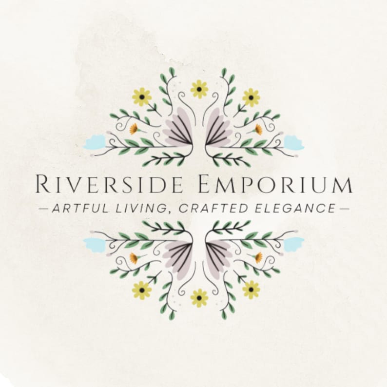 May include: A logo featuring the text RIVERSIDE EMPORIUM and the tagline ARTFUL LIVING, CRAFTED ELEGANCE in black serif font, centered between two symmetrical floral illustrations with green leaves, yellow flowers, and light blue accents.