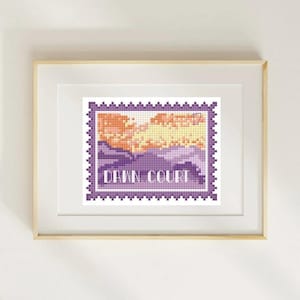 May include: A framed cross-stitch artwork featuring a landscape design within a purple postage stamp border. The artwork depicts a sunset with orange and yellow hues over purple mountains. The text "DAWN COURT" is displayed in white.