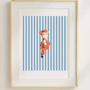 May include: Framed art print featuring a cartoon tiger character in orange and black stripes, standing against a backdrop of blue and white vertical stripes. The artwork is enclosed in a light wood frame.