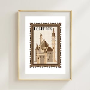 May include: A framed cross-stitch art piece featuring a detailed depiction of Hogwarts castle. The artwork is in shades of brown and beige, resembling a postage stamp. The word "HOGWARTS" is displayed at the top. The frame is a light wood color.