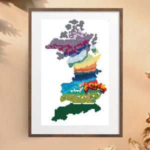 May include: A colorful cross-stitch embroidery of the fictional map of Westeros from the Game of Thrones series. The map is divided into different regions, each with a unique color scheme. The map is framed in a brown wood frame.