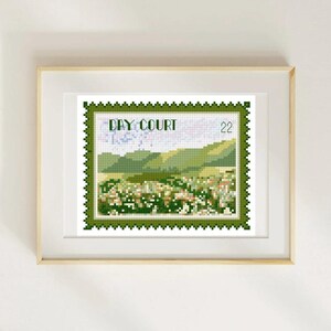 May include: Framed cross-stitch art featuring a postage stamp design with a landscape scene. The stamp has a green border and the text "DAY COURT" at the top. The landscape includes green hills and a field of white and green flowers. The number "22" is in the upper right corner.