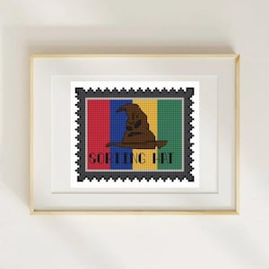 May include: A framed cross-stitch art piece featuring a brown Sorting Hat on a postage stamp design. The stamp has red, blue, yellow, and green stripes. The words "SORTING HAT" are stitched in black.