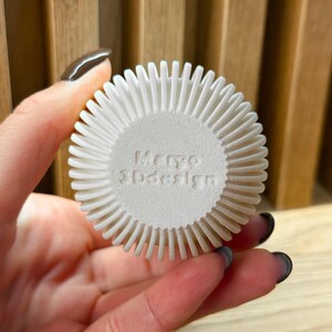 May include: White round object with a textured surface and the words "Mero 3Ddesign" printed on the front.