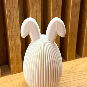 May include: White ceramic Easter bunny figurine with a ribbed egg-shaped body and two floppy ears.