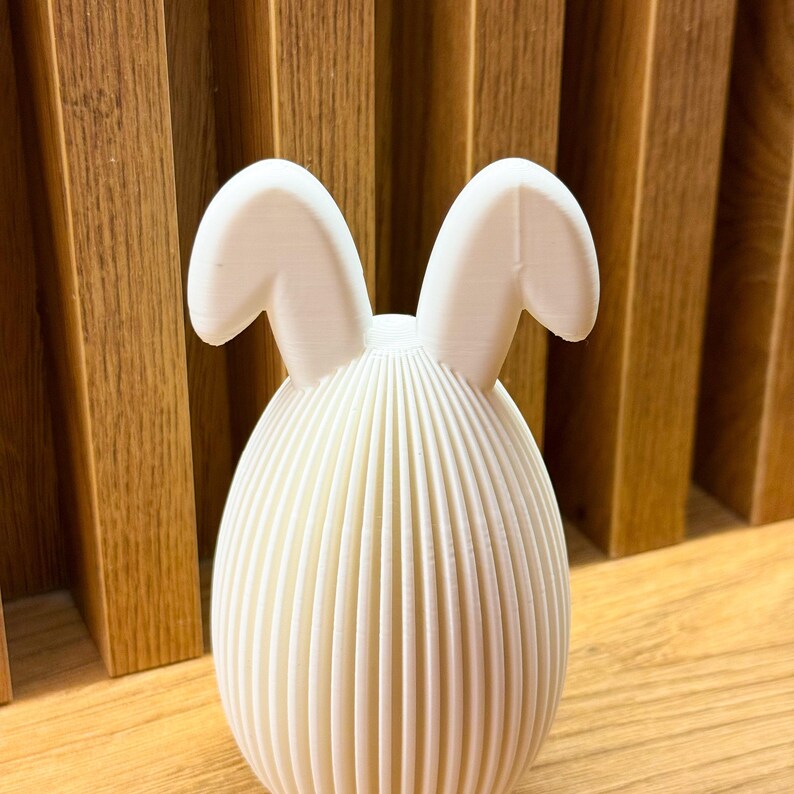 May include: White ceramic Easter bunny figurine with a ribbed egg-shaped body and two floppy ears.