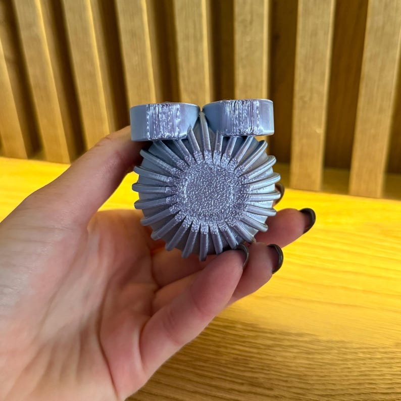 May include: A silver-colored, 3D printed, round object with a textured surface and two smaller, round, textured protrusions on top.