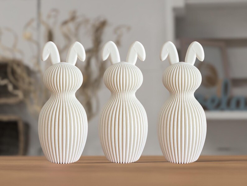 May include: Three white ceramic bunny figurines with a ribbed texture. The bunnies have long ears and a rounded body.