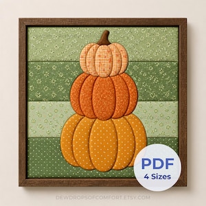 May include: A framed wall art piece featuring a stack of three fabric pumpkins in orange and tan patterns. The pumpkins are set against a background of horizontal green fabric strips with small white floral and dot prints. A white circular label reads PDF 4 Sizes.