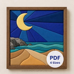 Op de afbeelding: Een vierkant ingelijst kunstwerk aan de muur met een gelaagd stoffen ontwerp van een nachtelijk strandtafereel. Een gele halve maan bevindt zich in een donkerblauwe lucht boven turquoise oceaangolven, grijze rotskliffen en beige zandduinen.