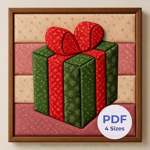 May include: A framed fabric wall art piece featuring a three-dimensional gift box design with a red bow. The box is green with a red ribbon pattern, set against a background of horizontal fabric strips in beige, pink, and red. Text reads PDF 4 Sizes.