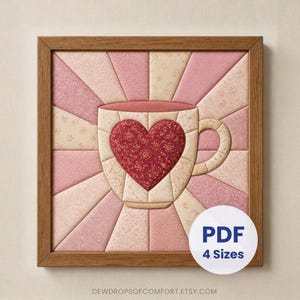 May include: A square framed fabric quilt block featuring a central coffee mug with a dark red floral heart appliqué. The background consists of radiating light pink and cream fabric panels. A white circular label displays the text PDF 4 Sizes.