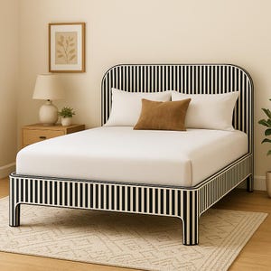 May include: A modern bed frame with a black and white striped design. The bed has a white mattress, white pillows, and a brown decorative pillow. A wooden nightstand with a lamp and a framed picture are visible in the background.