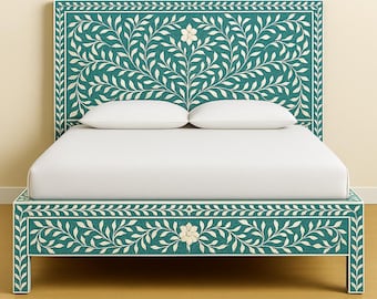 May include: A teal and white floral patterned bed frame with a matching headboard. The headboard and frame feature a repeating leaf design and a central flower motif. Two white pillows rest on the bed.