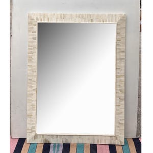 May include: A large rectangular mirror with a white mosaic frame. The frame is made of small, irregular pieces of white tile.