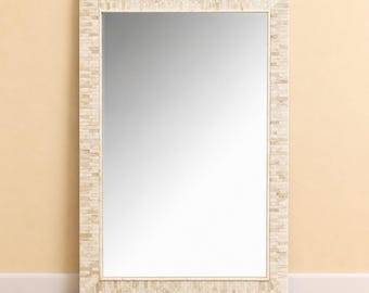 May include: A rectangular wall mirror featuring a wide frame constructed from numerous small, light beige and cream-colored rectangular tiles arranged in a stacked, brick-like pattern. The reflective glass surface is clear and smooth.