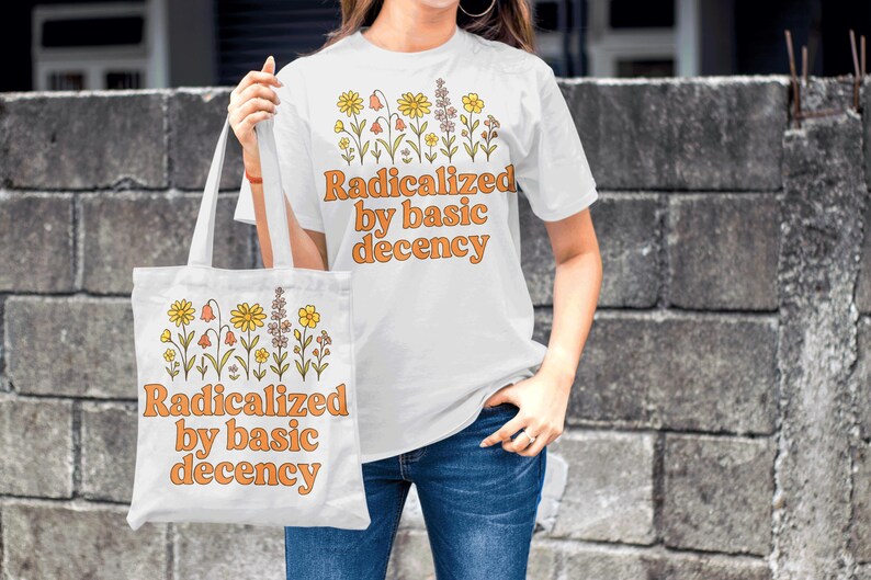 May include: White t-shirt and tote bag with the text "Radicalized by basic decency" in orange. Both items feature a floral design in yellow, orange, and brown. The person is wearing blue jeans.
