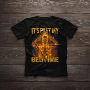 May include: Black t-shirt featuring a fiery skeleton graphic. The skeleton is depicted with flames and is holding its head. The text "IT'S PAST MY BEDTIME" is printed above and below the graphic in gold.