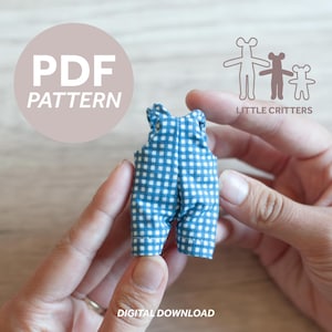 Könnte beinhalten: Eine Miniatur-Latzhose mit blauem und weißem Vichy-Muster wird von einer Person in den Händen gehalten. Das Bild enthält den Text "PDF PATTERN" in einem hellrosa Kreis und die Worte "DIGITAL DOWNLOAD" unten. Das Little Critters-Logo ist ebenfalls sichtbar.