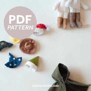 Puede incluir: Una colección de sombreros de tela en miniatura y una capa con capucha, que incluye un sombrero de pirata, un sombrero de vaquero y un gorro de Papá Noel. La imagen también presenta dos pequeñas figuras con cuerpos blancos y botas marrones. El texto "PDF PATTERN" está en un círculo.