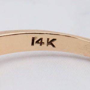May include: Close-up of the inside of a gold ring with the inscription "14K" on the band.