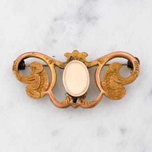 Op de afbeelding: Gouden filigraan broche met een lege ovale cameo. De broche heeft een delicaat, versierd ontwerp met een bloemenmotief.