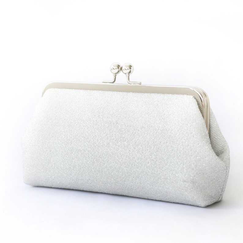 A shimmery silver clutch bag in silver mounted on a double metal frame in silver tone adorned with kisslock 2-ball clasp in the centre