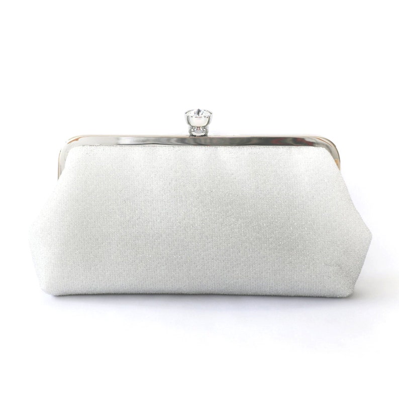 A shimmery silver clutch bag in silver mounted on a double metal frame in silver tone adorned with a centre 26mm diameter crystal in the centre.