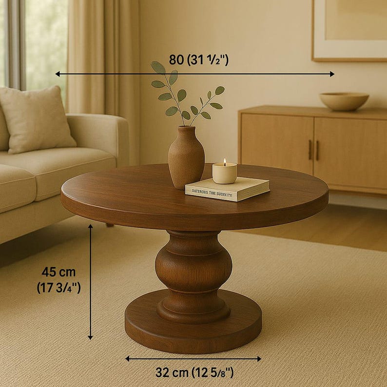 May include: A round wooden coffee table with a pedestal base. The table is 31 1/2 inches wide, 17 3/4 inches tall, and 12 5/8 inches in diameter. The table is brown and has a natural wood finish.