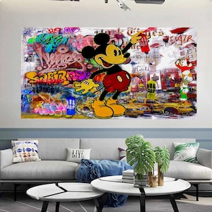 Op de afbeelding: Een kleurrijke graffiti-kunstprint met Mickey Mouse die een spuitbus vasthoudt voor een achtergrond van New York City. De print bevat de woorden "New York Times" en "Esquire".