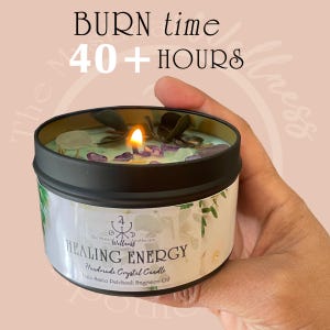 May include: A lit, handmade crystal candle in a black tin, labeled "Healing Energy." The candle has a burn time of 40+ hours and is decorated with crystals and leaves. The candle is held in a person's hand.