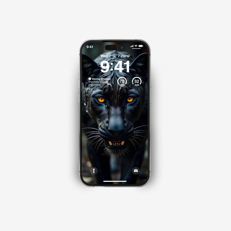 Puede incluir: Un pantera negra con ojos amarillos brillantes mira fijamente a la c&aacute;mara. La pantalla del tel&eacute;fono muestra la hora 9:41 y la fecha mi&eacute;rcoles 7 de julio a las 7:29 PM. El tel&eacute;fono tambi&eacute;n muestra un icono de fase lunar, una temperatura de 70 grados y un nivel de humedad del 32%.