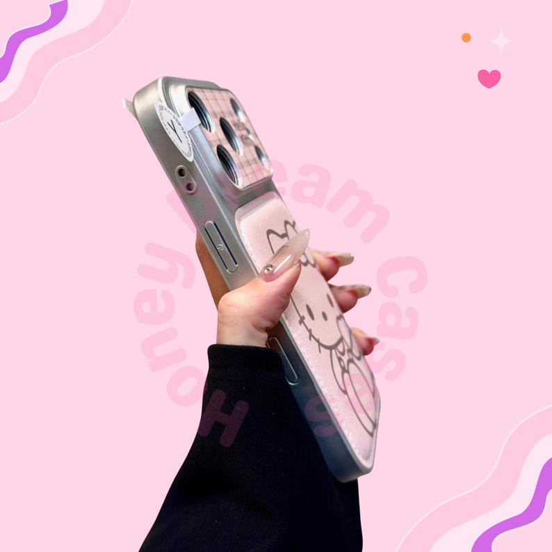 K&ouml;nnte beinhalten: Silberne Handyh&uuml;lle mit einem rosa Hello Kitty-Design und einem Herz. Die H&uuml;lle hat ein rosa-wei&szlig;es Karomuster in der N&auml;he der Kamera. Die H&uuml;lle befindet sich vor einem rosa Hintergrund.