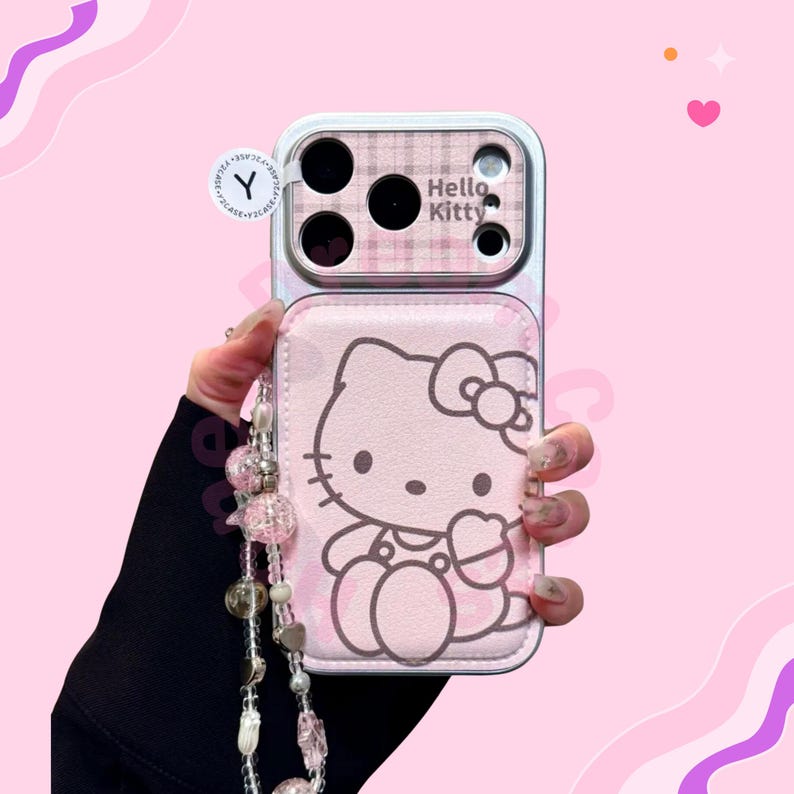 K&ouml;nnte beinhalten: Rosa Handyh&uuml;lle mit Hello Kitty-Design. Die H&uuml;lle hat ein Karomuster um die Kamera und die Aufschrift "Hello Kitty". Ein Perlenband ist an der H&uuml;lle befestigt.