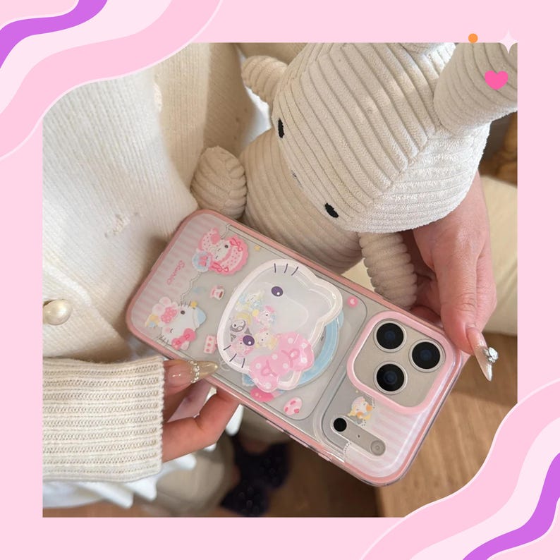 Op de afbeelding: Een doorzichtige telefoonhoes met een roze rand en een cartoonontwerp. De hoes heeft een 3D-karakter en andere decoratieve elementen. De telefoonhoes wordt vastgehouden in de buurt van een wit knuffeldier.