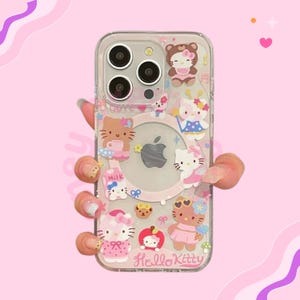 May include: Clear phone case decorated with Hello Kitty characters in different outfits. The case has a pink background with multiple Hello Kitty designs, including one holding a cup and another with a bow. The words "Hello Kitty" are printed at the bottom.
